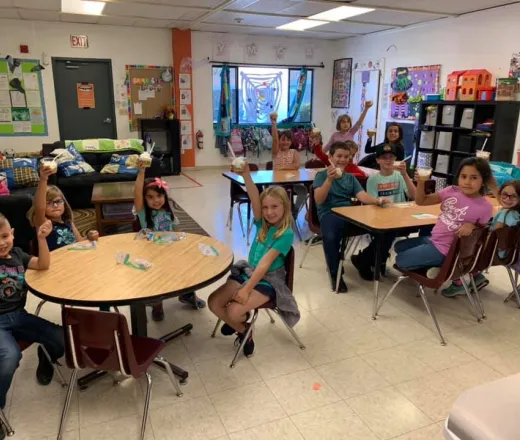 Many kids at 3 tables during snack time