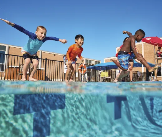Elementary aged kids jumping into the pool.