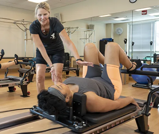 instructor helping YMCA member on pilates reformer machine